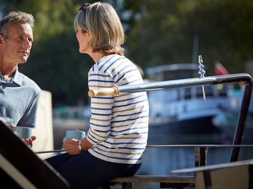 Man and woman share a hot drink on a boat